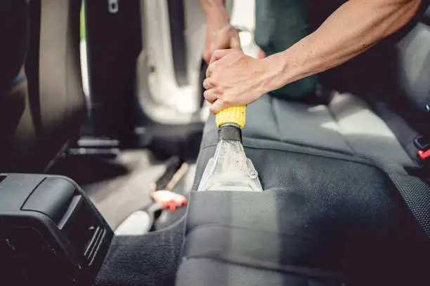 Professional detailer steam cleaning car seat upholstery